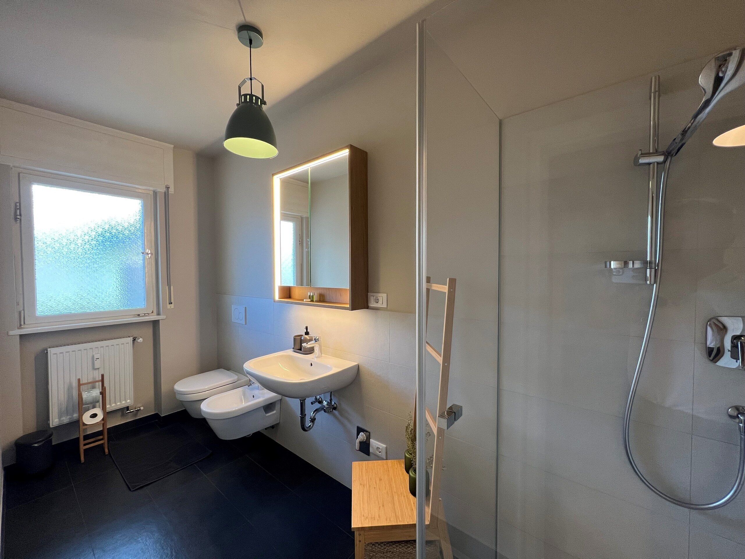 Un baño moderno con inodoro, lavamanos y ducha.