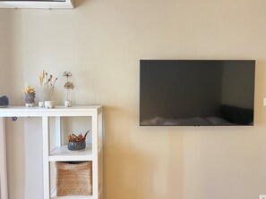 Ein Zimmer mit einem weißen Konsolentisch, einem wandmontierten Flachbildfernseher und einem gewebten Korb auf der unteren Ablagefläche.