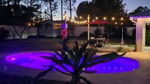 A backyard with a swimming pool, outdoor seating, string lights, and a covered patio area. - Your Palm Coast Pool House! (Palm Coast)