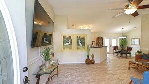 A spacious living area with a high ceiling, a dining area, and a kitchen in the background. - Your Palm Coast Pool House! (Palm Coast)
