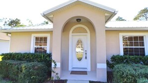 A two-story house with a beige facade, a central arched entrance, and a small front porch. - Your Palm Coast Pool House! (Palm Coast)