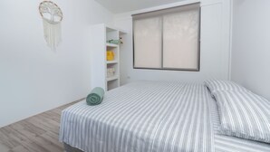 Un dormitorio con cama, armario, estante con toallas y un adorno en la pared.