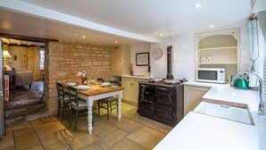 A compact kitchen with a wooden table, a stove, and a microwave. - Mouse Manor - pet friendly, Longborough near Stow-on-the-Wold (Longborough)