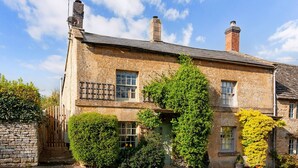 A stone building with multiple chimneys, a wooden fence, and lush greenery. - Mouse Manor - pet friendly, Longborough near Stow-on-the-Wold (Longborough)