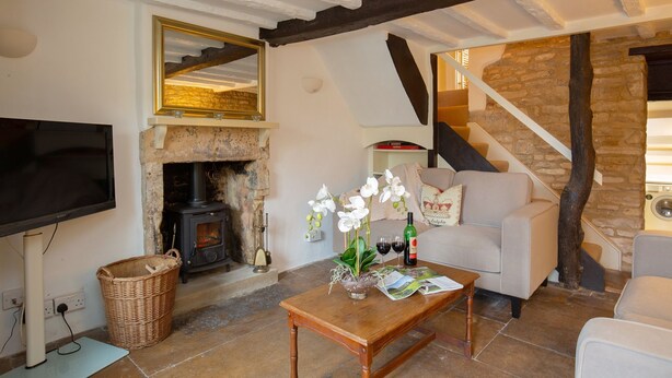 A cozy living room with a stone fireplace, a television, a sofa, and a staircase leading to an upper level. - Mouse Manor - pet friendly, Longborough near Stow-on-the-Wold (Longborough)