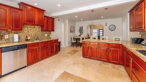 A spacious kitchen with granite countertops, wooden cabinets, and a dishwasher. - Ocean Breeze Getaway  (Deerfield Beach)