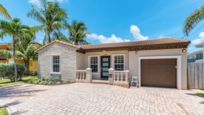 A two-story house with a stone facade, a brown garage door, and a paved driveway. - Ocean Breeze Getaway  (Deerfield Beach)