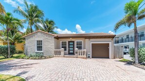 A two-story house with a stone facade, a tiled roof, and a paved driveway. - Ocean Breeze Getaway  (Deerfield Beach)