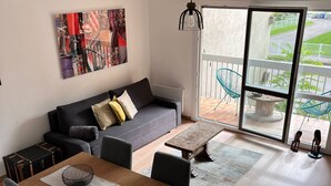 A modern living room with a sofa, a dining table with chairs, a large window, and a balcony with chairs. - Close to Dijon city center, ideal for a leisure or business stay  (Dijon)