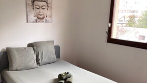 A bedroom with a bed, pillows, a hanging light fixture, and a window. - Close to Dijon city center, ideal for a leisure or business stay  (Dijon)