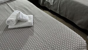 Una habitación de hotel con dos camas, una mesita de noche con lámpara y una toalla doblada en el suelo.