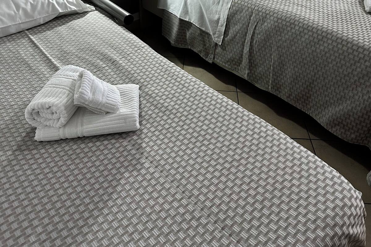 Una habitación de hotel con dos camas, una mesita de noche con lámpara y una toalla doblada en el suelo.