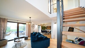 A spacious living area with a blue sofa, a dining table, and a staircase. - Villa Fusion with Pool (Sukošan)