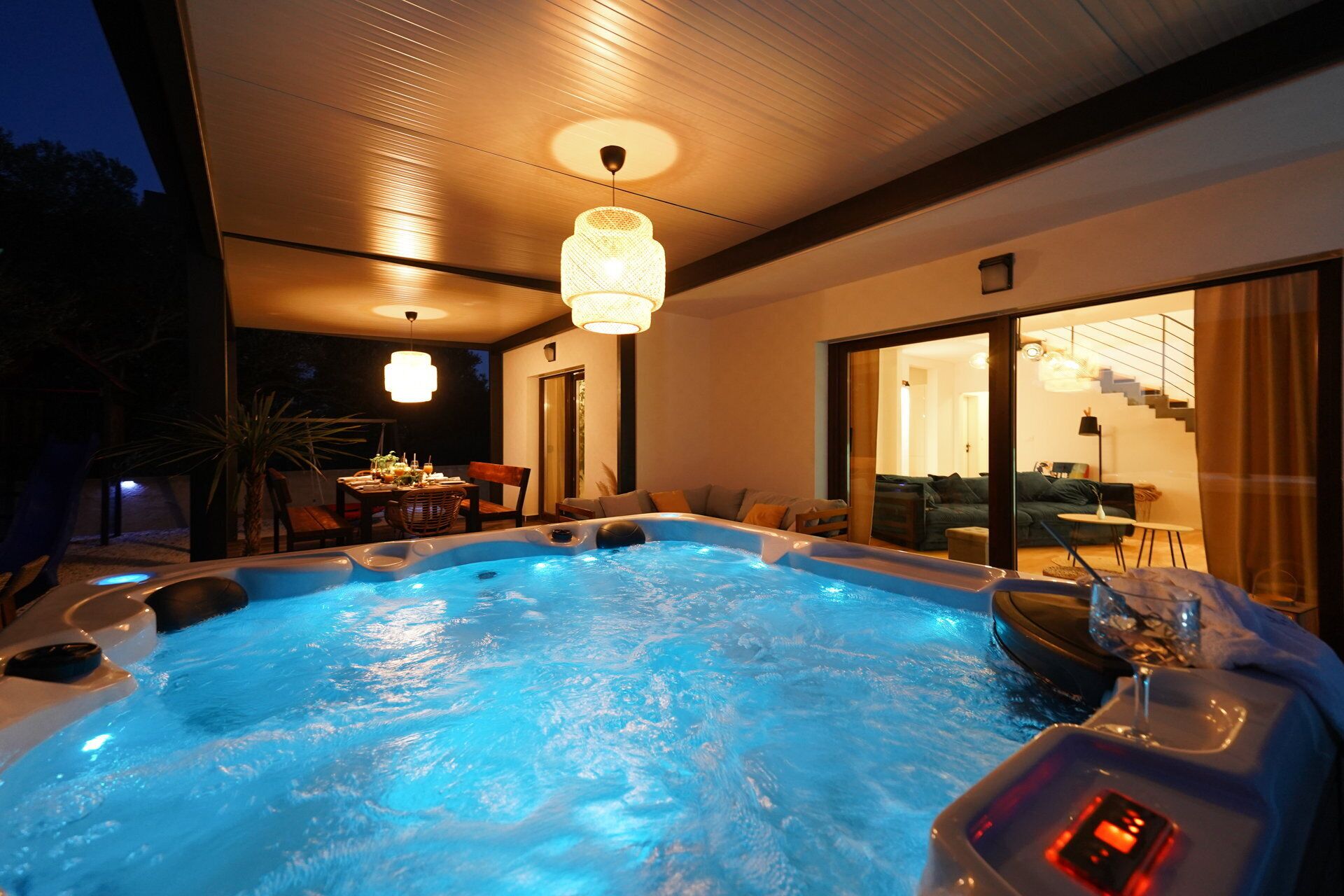 Ein Whirlpool mit einer digitalen Steuerung, ein Essbereich mit Tisch und Stühlen sowie eine Treppe zu einer oberen Ebene.