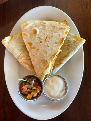 Une assiette avec trois quesadillas et deux petits bols de condiments.