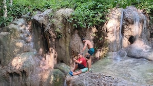 A natural rock formation with a waterfall and a pool of water at the base.