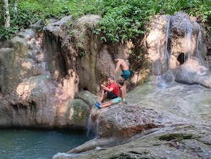 A natural rock formation with a waterfall and a pool of water at the base.
