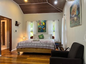 Une chambre à coucher avec un lit, une chaise, un tableau et une fenêtre.