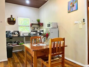 A compact kitchen with a dining table, chairs, a microwave, and a refrigerator.