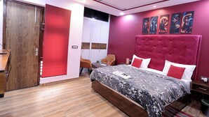 A bedroom with a large bed, a ceiling fan, a wooden wardrobe, and a red accent wall.