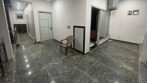 A hallway with a marble floor, a chair, and a door leading to another room.