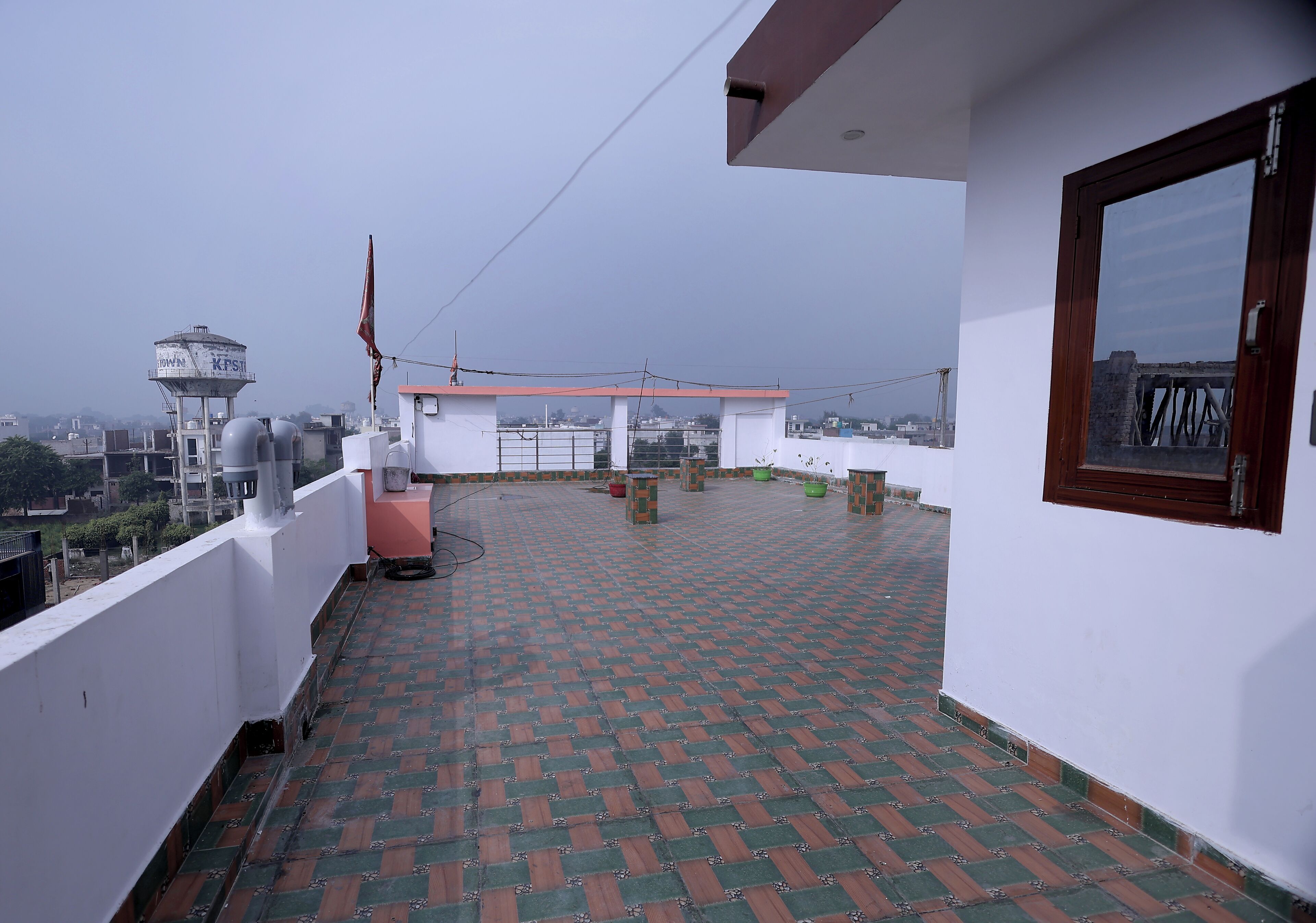 Una terraza en la azotea con suelo estampado, un tanque de agua y vistas de la ciudad.