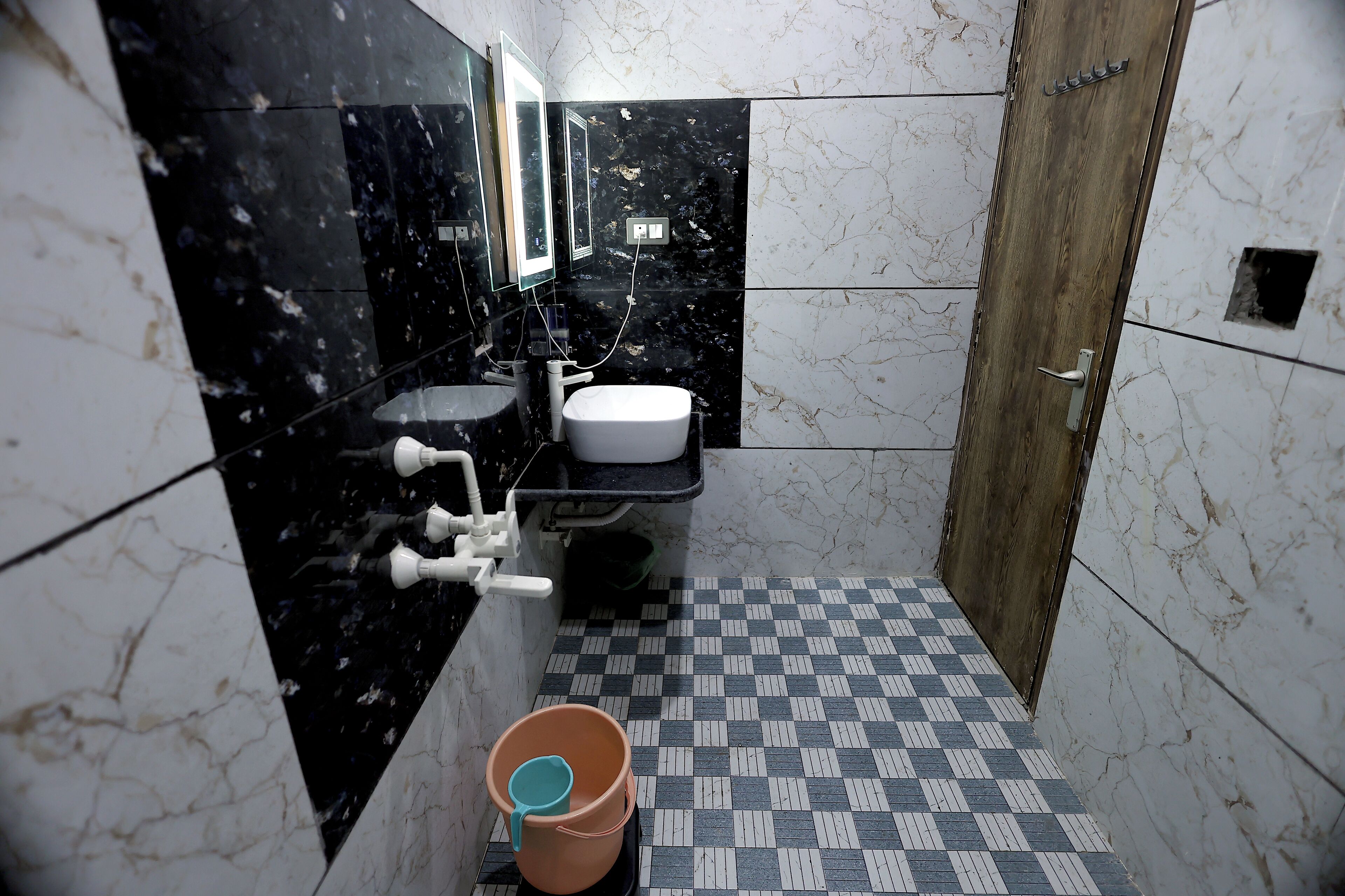 A bathroom with a black marble sink, a white toilet, and a checkered floor.