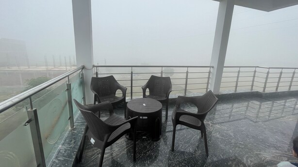 A balcony with a glass railing, a round table, and four chairs.