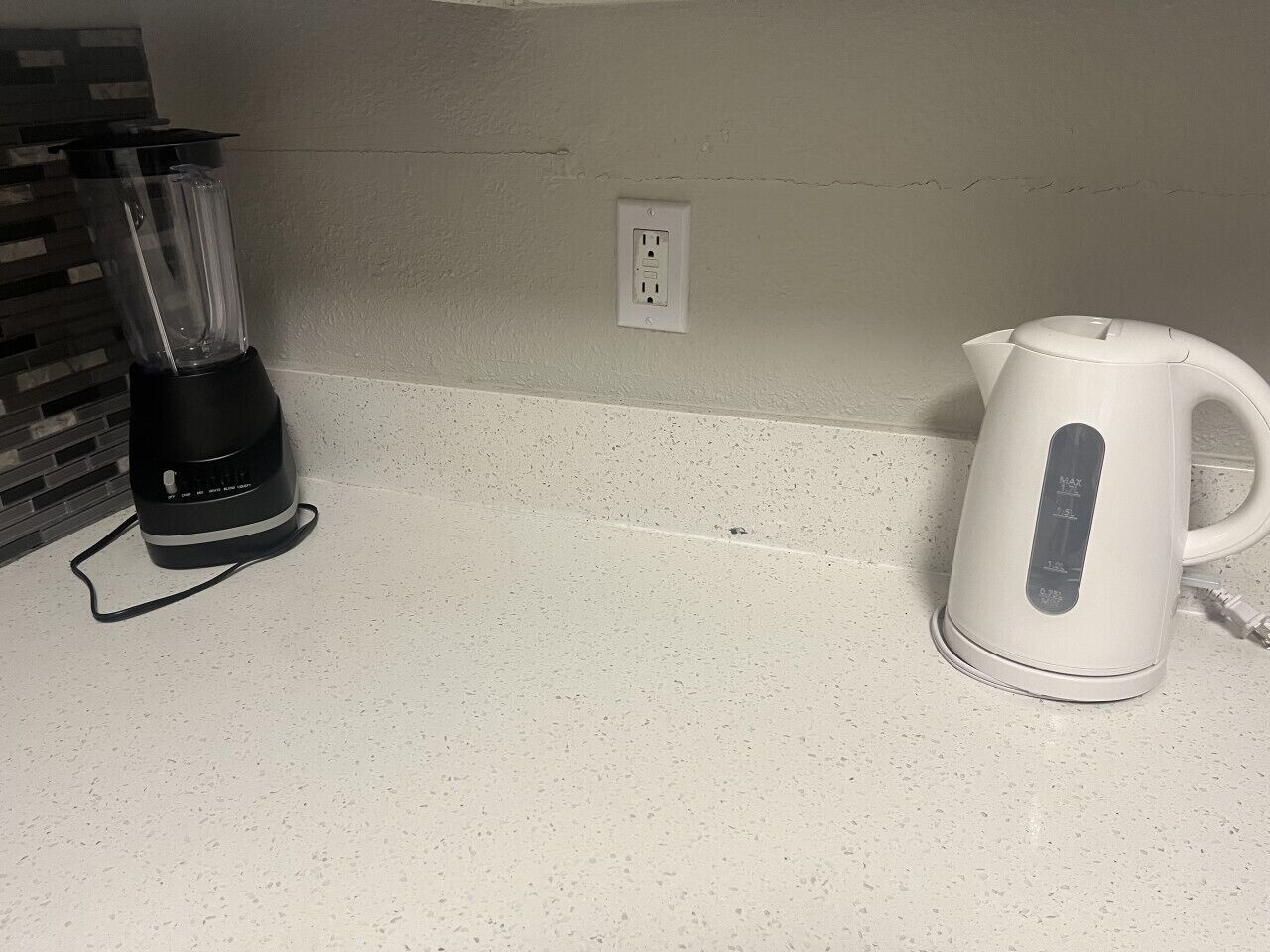 A kitchen counter with a blender and a kettle.