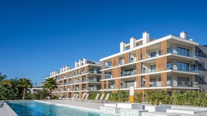 Un hôtel moderne à plusieurs étages, doté d’une piscine, de balcons et offrant une vue sur un ciel d’un bleu éclatant.