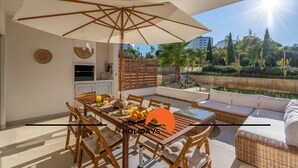 Un espace repas comprenant une table, des chaises et un grand parasol.