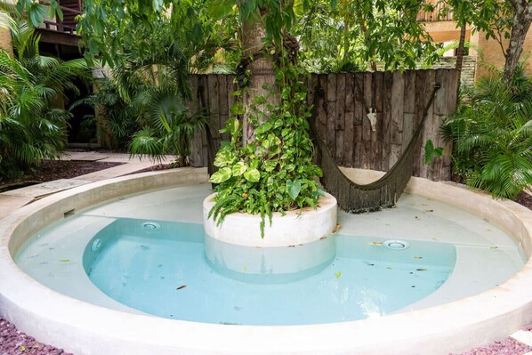 Relax in a serene hot tub surrounded by lush greenery and tropical plants.
