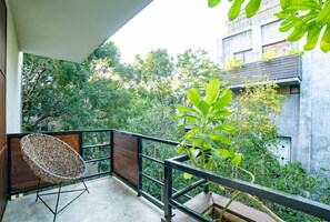 Enjoy the serene views from this balcony with a comfortable chair and a potted plant.