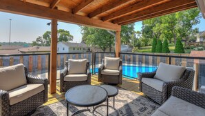 Un patio techado con muebles de mimbre y vistas a una piscina.
