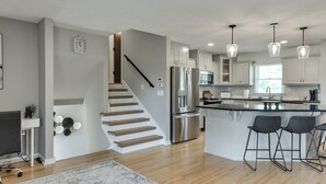 Una cocina moderna con una isla central, electrodomésticos de acero inoxidable e iluminación colgante.