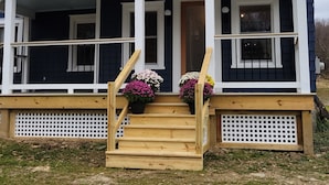 A two-story house with a front porch, wooden steps, and potted flowers.
