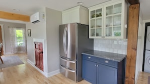 A modern kitchen with a stainless steel refrigerator, blue cabinets, and a built-in washing machine.
