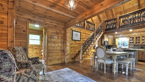 A cozy cabin interior with a wooden interior, a dining area with a table and chairs, and a staircase leading to an upper level. - Cabin in Blue Ridge: Hot Tub|Fire Pit|Fooseball (Cherry Log)