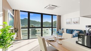 A modern dining area with a large window, a dining table set with plates, glasses, and a plant. - B213 - Deluxe 1 Bedroom Apartment (Sint Maarten)