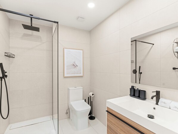 A modern bathroom with a shower, toilet, and sink. - B213 - Deluxe 1 Bedroom Apartment (Sint Maarten)