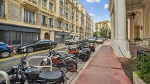 A row of parked motorcycles along a city street with historic buildings on one side.