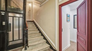 A staircase with a handrail, a door with a red frame, and a wall with a picture.