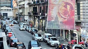 A busy urban street with multi-story buildings, parked cars, and pedestrians. - At the Naples Binario REGINA ROOM (Napoli)