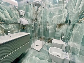 Een moderne badkamer met een glazen douchecabine, een wastafel, een toilet en een bidet.