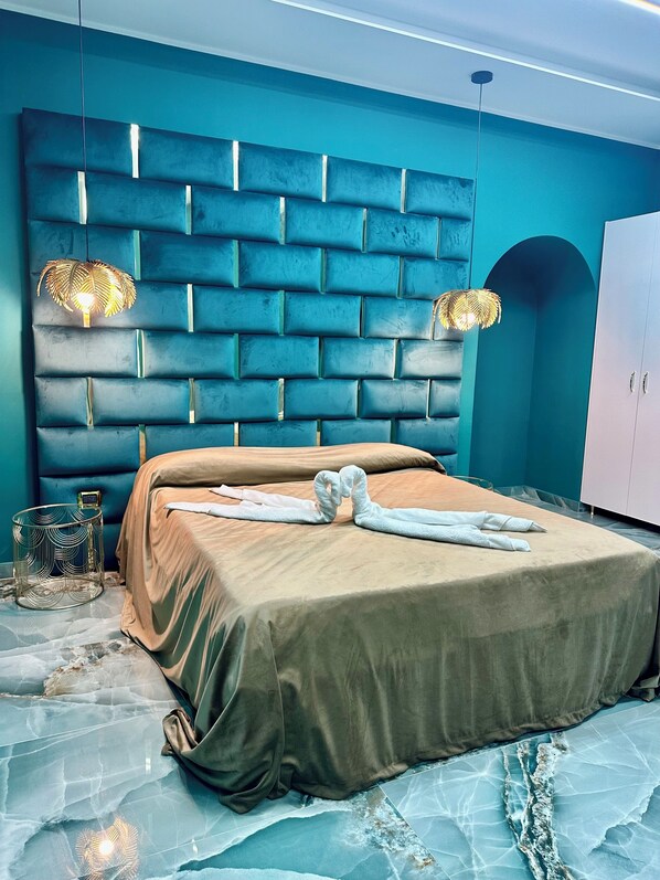 A modern bedroom with a blue brick-patterned headboard, a bed with a beige cover, and two wall-mounted lamps.