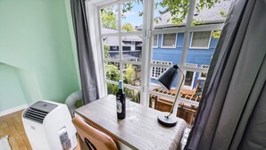 A small room with a window, a table, a chair, a heater, and a lamp. - Sunlit Cottage Capitol Hill (Seattle)