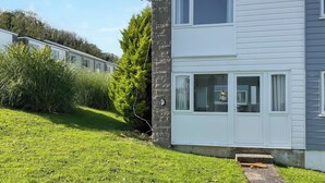 A two-story house with a white exterior, a satellite dish, and a small step leading to the front door. - Great property close to Freshwater East Bay, perfect for a family break. (Freshwater East)