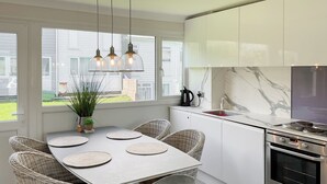 A modern kitchen with a dining table, wicker chairs, a built-in oven, and a view of the outside. - Great property close to Freshwater East Bay, perfect for a family break. (Freshwater East)