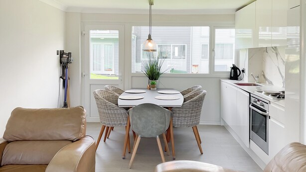 A modern kitchen with white cabinets, a dining table with wicker chairs, and a leather sofa. - Great property close to Freshwater East Bay, perfect for a family break. (Freshwater East)