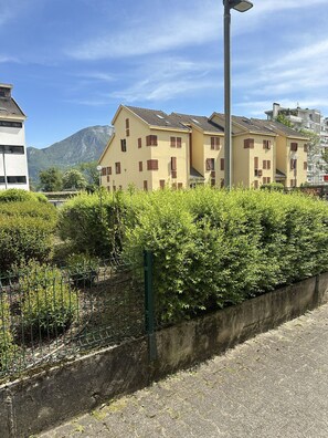 Un immeuble résidentiel à plusieurs étages, doté d’un toit plat, d’un lampadaire et avec une montagne en arrière-plan.